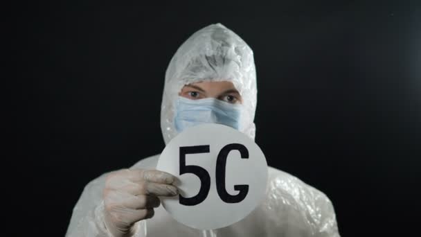 L'homme tient un badge 5G en costume blanc contre le coronovirus, met un capuchon en aluminium lève le doigt — Video