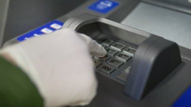 Eldiven içinde ATM 'nin düğmelerine tıklayın, bankaya yakın çekim parolasını girin, halka açık bir yerde koronavirüs