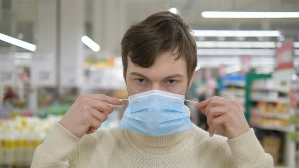 A young man puts on a medical mask to protect himself from the epidemic — Stock Video