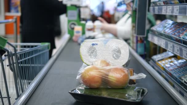 チェックアウト時のコンベアベルト上のプラスチック包装の製品クローズアップトイレタリーペーパー、玉ねぎ — ストック動画