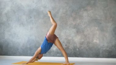 Kız parlak stüdyoda yoga yapıyor, Asana 'yı havada boylamsal sicimle seslendiriyor.
