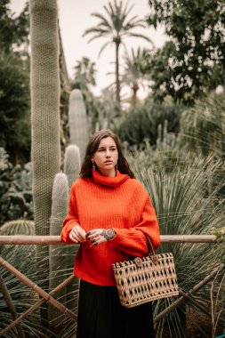 Genç kadının yanına kaktüs kırmızı kazak ile.