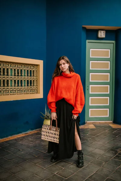 Frau Steht Mit Tasche Und Rotem Pullover Vor Buntem Haus — Stockfoto