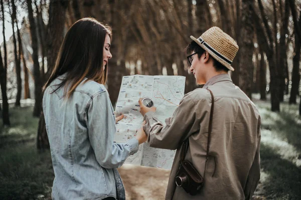 young couple hikers with map in forest