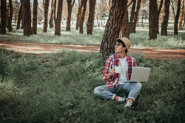 young man using laptop in forest