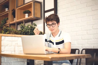 yakışıklı delikanlı kafede dizüstü bilgisayar kullanarak 