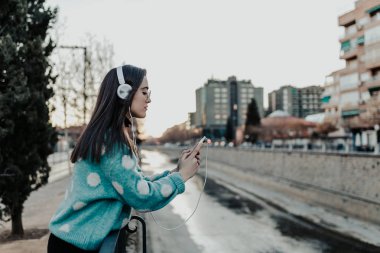Şehirde telefon kullanarak ve müzik güzel bir kadın. Mobil ve zevk müzik kullanarak parkta güzel bir kadın. Kadın sokakta mobil bir mesaj yazma
