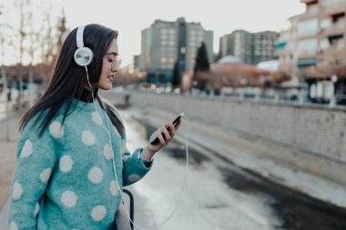 Şehirde telefon kullanarak ve müzik güzel bir kadın. Mobil ve zevk müzik kullanarak parkta güzel bir kadın. Kadın sokakta mobil bir mesaj yazma