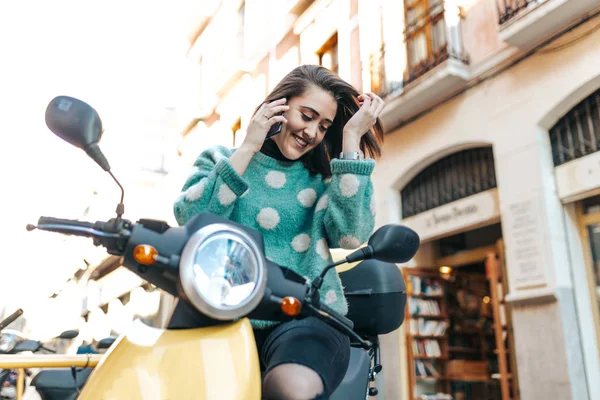 Beautiful woman on the motorcycle using the cellphone. Woman sitting on the motorcycle calling by phone. Woman finishing the work day