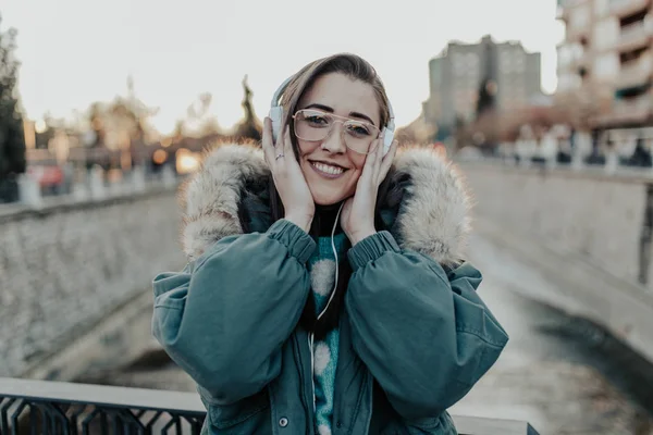 Beautiful woman with glasses listening to music on the street. Beautiful woman enjoying music in the park. Young man listening to music on his headphones