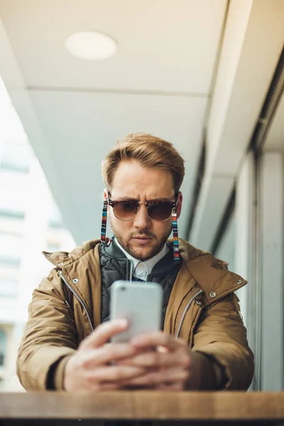 Mladý Muž Nosí Sluneční Brýle Pózuje Venku Pomocí Smartphonu Stock Obrázky