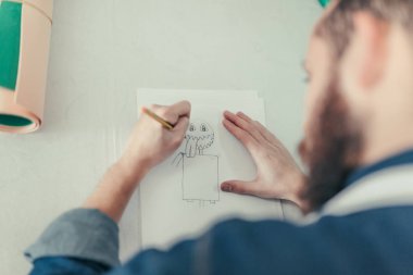 El Sanatları Atölyesi çalışma erkek tasarımcısında. Genç tasarımcı masanın üzerinde çizim