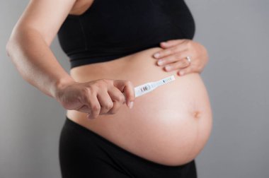 Hamile bir kadının elinde yakın çekim hamilelik testi