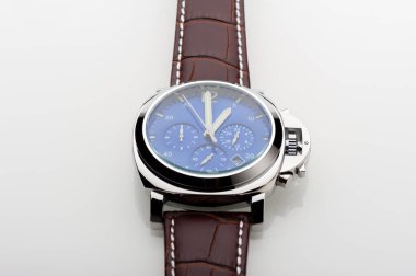 Mavi kadranlı lüks moda saati ve beyaz arka planda kahverengi timsah derisi deri saat bandı.