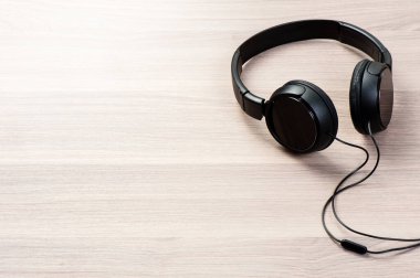 Kablolu siyah kulaklık ahşap arka planda izole