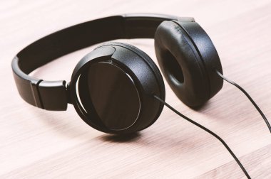Kablolu siyah kulaklık ahşap arka planda izole