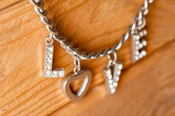 爱情这个词是从女人的饰物 金属链 心形和钻石 中提取出来的 — 图库照片