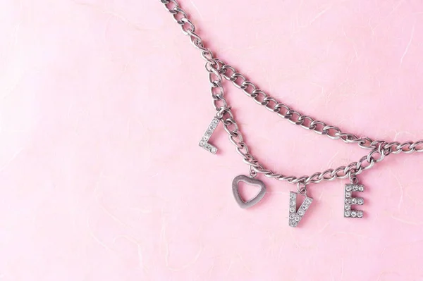 abstract the word love from woman accessory (metal chain, heart shaped and diamonds)