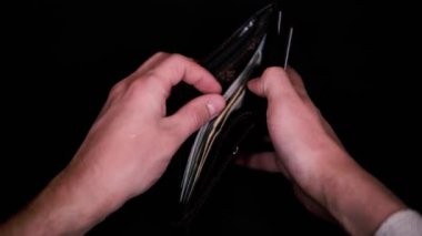 Beyaz gömlekli bir adam siyah bir cüzdan açar ve parayı sayar. Para kazanma ihtiyacı. Bir ABD vatandaşının ortalama kazancı.