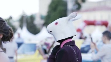 MINSK, BELARUS - 15 Haziran 2019: Mor takım elbiseli tavşan maskeli bir animatör insanlar arasında yürüyor. Okul balosu gecesi..