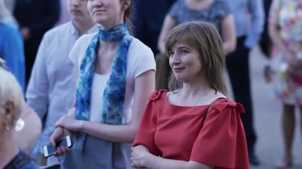 发自比利时明斯克 2019年6月15日 一位身穿红色礼服的女性站在人群中 一边听着演讲者讲话 一边微笑着 — 图库视频影像