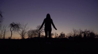 Yoga yapan bir kızın silueti gibi. Sunset 'teki parkta yoga yapan bir kız. Rahatlama ve Meditasyon Temelleri. Bilinçli Davranış.