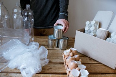 İnsanlar farklı türde çöpleri dizer, kağıtları, plastik kutuları ve yiyecek atıklarını ayırır.