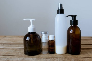 Kozmetik ürünleri için ahşap bir masa üzerinde konteynırlar. Kraft kağıdı, sprey, yağ, jel, kahverengi cam, kozmetik bileşimi.