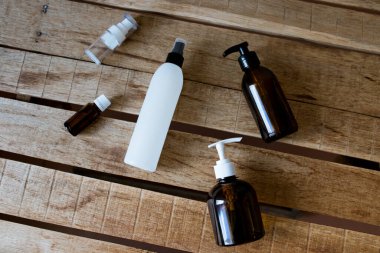 Kozmetik ürünleri için konteynırlar ahşap bir masanın üzerinde uzanıyor. Kravat kağıdı, sprey, yağ, jel, kahverengi cam, kozmetik bileşimi.