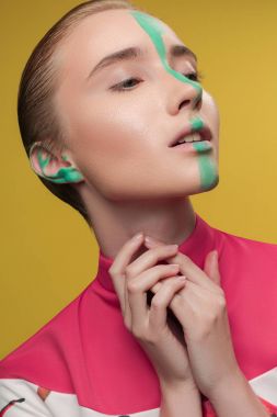 Moda Güzellik Portresi geri çekti-sarışın kız yüz orta üzerinde boya yeşil hat ile sola, seyir ile ellerini boynuna yakınındaki parlak pembe bluz Sarı zemin üzerine katlanmış