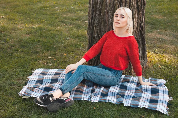 Woman sitting on lawn in park — Stock Photo, Image