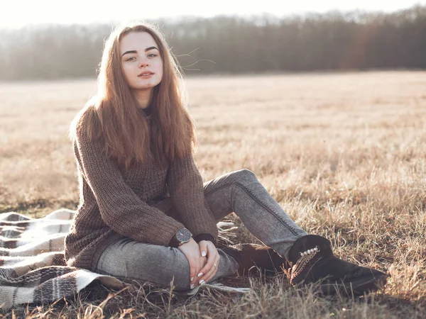 Woman sitting on plaid in field — Stock Photo, Image