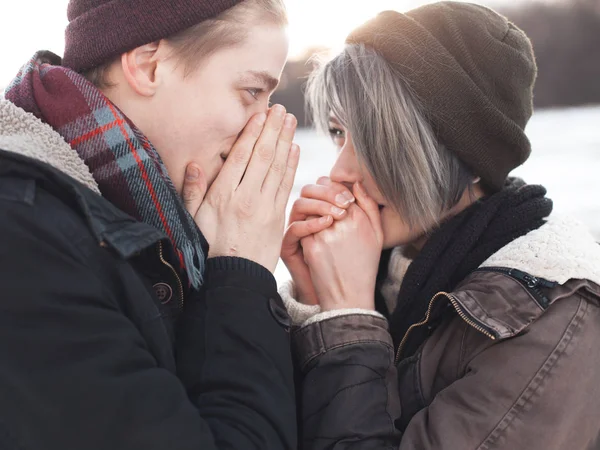 Jeune femme et homme se réchauffant les mains — Photo