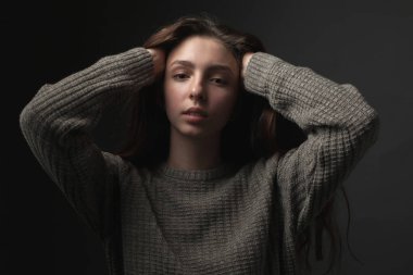 Eller başının üstüne gri arka plan üzerinde olan kadın portresi