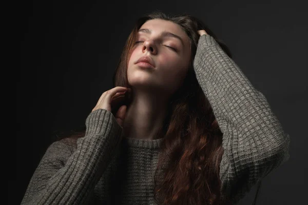 Portrait of young woman with closed eyes on dark background