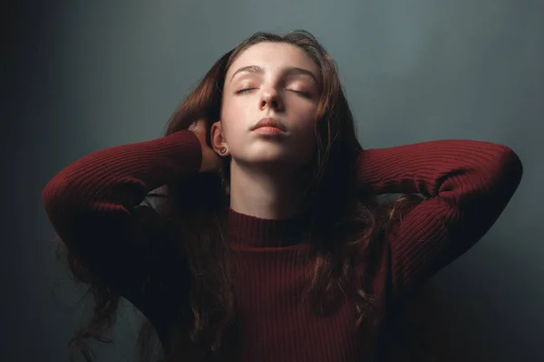 Portrait of young woman with closed eyes on grey background