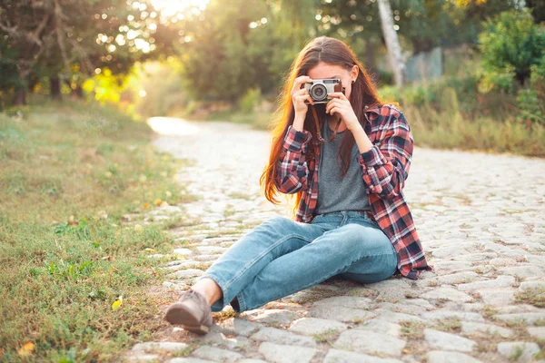 woman sitting on paving stone road and taking photo