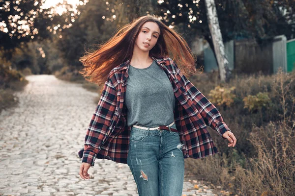 Young woman walking on countryside road on blurred background