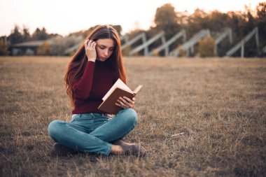 stadyum alanında oturup ve kitap okuma genç kadın