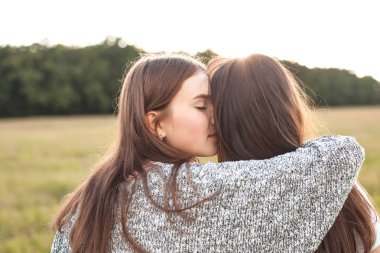 İki kız sahada günbatımı sırasında sarılma