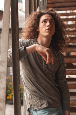 paslı merdivenler üzerinde duran kıvırcık saçlı olan genç adam