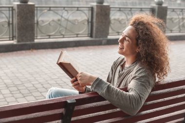 genç adam bankta kitap okuma