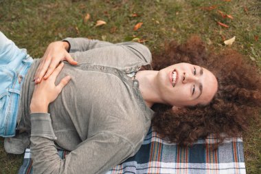 genç adam ekose Park çimenlerin üzerinde yatan gülümseyen