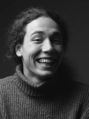 Studio kıvırcık saçlı genç adam gülümseyen tek renkli portresi