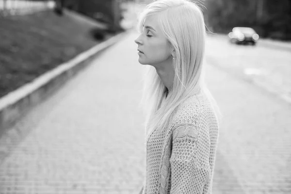 Monochrome photo in profile of young blond woman walking on city street
