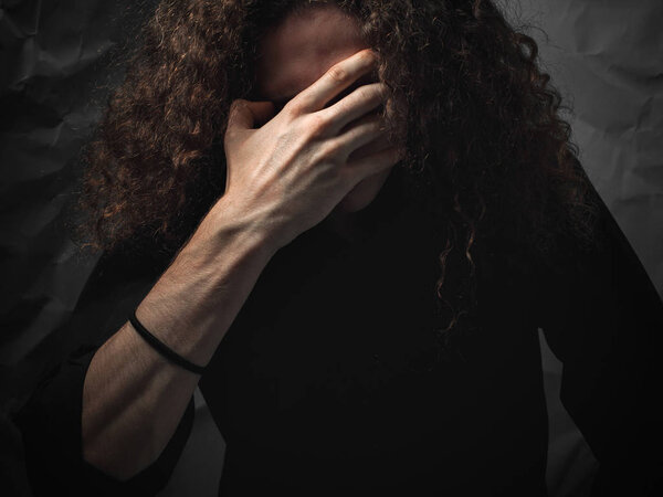 Portrait of young man with curly hair in desperateness