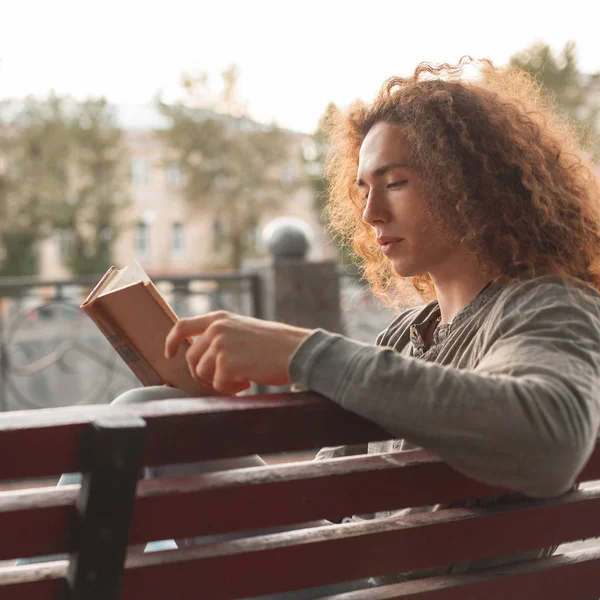 Genç adam parkta kitap okuyor.