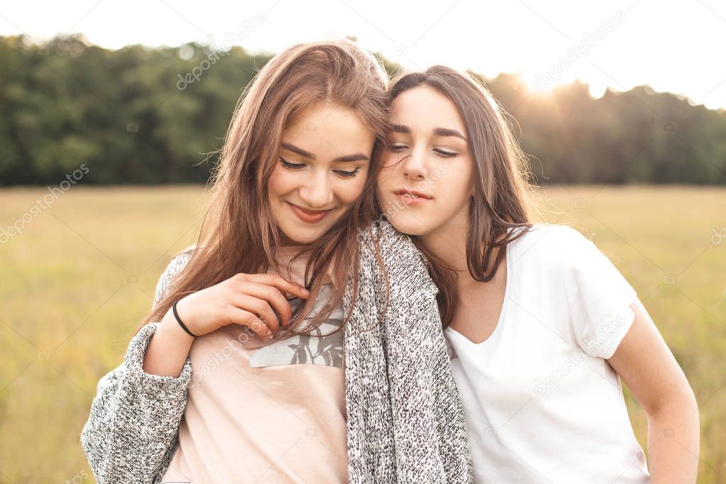 Two women with closed eyes posing on field