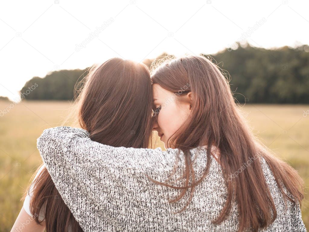Two girls hugging on green field in daytime