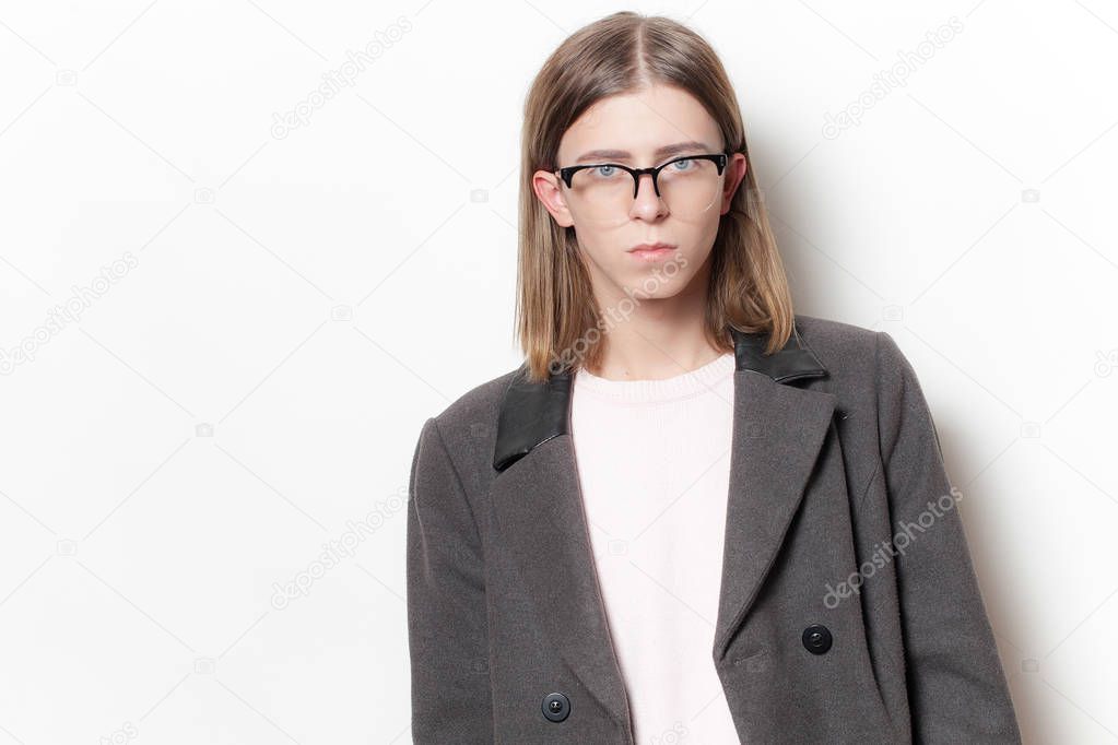 Portrait of androgynous young man in glasses and coat